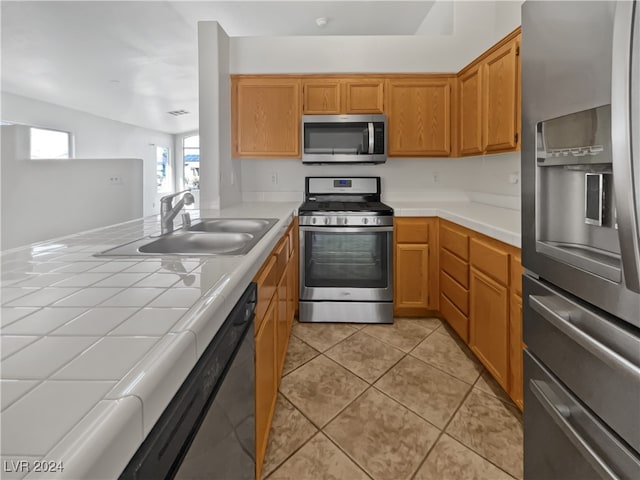 kitchen featuring light tile patterned flooring, vaulted ceiling, stainless steel appliances, tile countertops, and sink