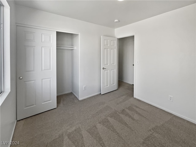 unfurnished bedroom featuring light colored carpet and a closet