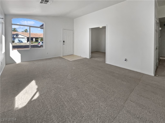 unfurnished living room featuring carpet floors and vaulted ceiling