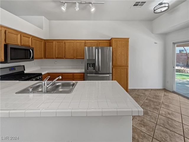 kitchen with tile counters, appliances with stainless steel finishes, light tile patterned flooring, and sink