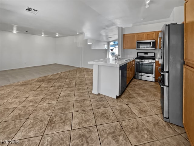 kitchen with kitchen peninsula, appliances with stainless steel finishes, light tile patterned floors, and sink