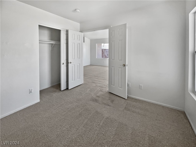 unfurnished bedroom featuring light colored carpet and a closet