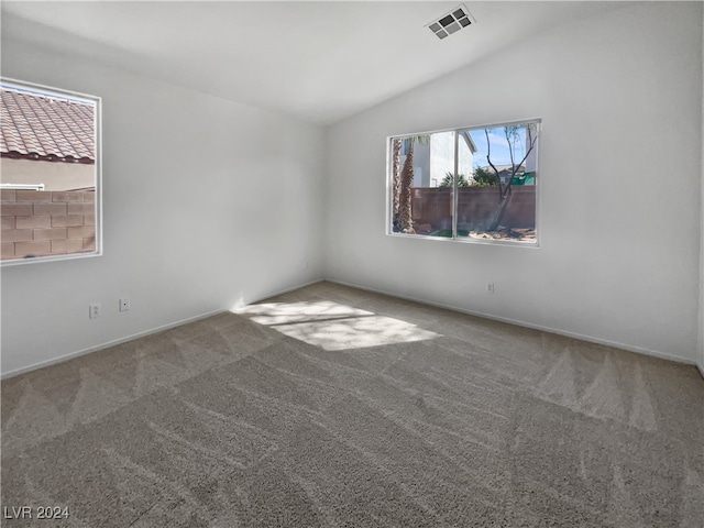 carpeted empty room with vaulted ceiling