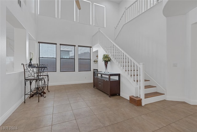 staircase with a high ceiling, ceiling fan, and tile patterned floors