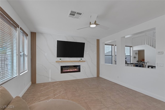 unfurnished living room with a premium fireplace, a wealth of natural light, and ceiling fan