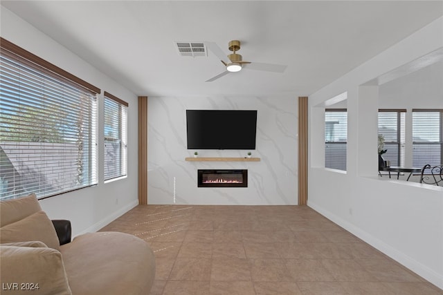 living room featuring ceiling fan, light tile patterned flooring, and a high end fireplace