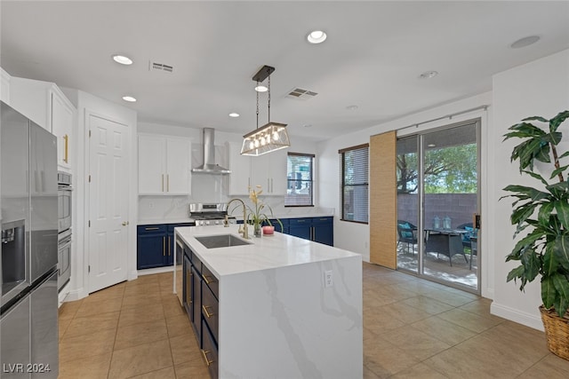 kitchen featuring blue cabinets, white cabinets, an island with sink, pendant lighting, and sink