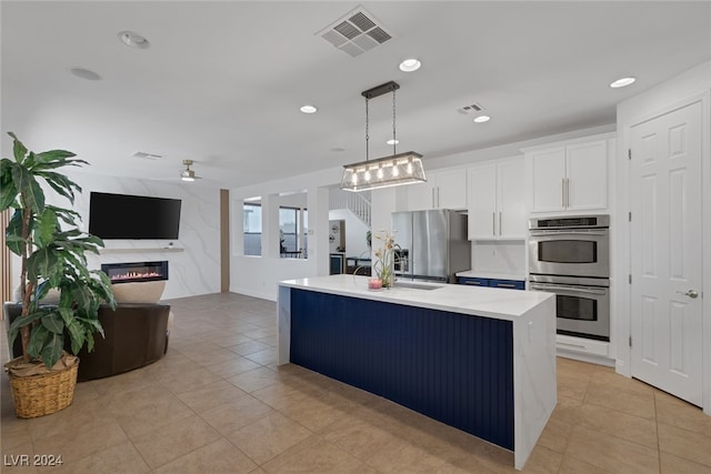 kitchen featuring pendant lighting, white cabinets, light tile patterned floors, a kitchen island, and stainless steel appliances