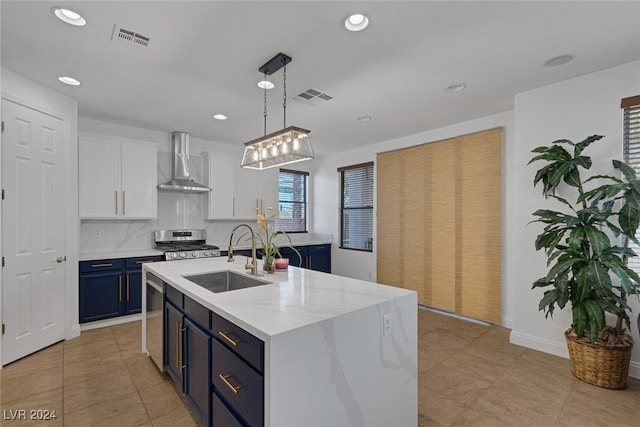 kitchen with sink, white cabinetry, wall chimney range hood, decorative light fixtures, and blue cabinetry