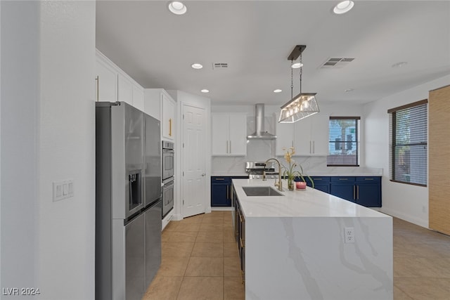 kitchen featuring blue cabinets, white cabinets, appliances with stainless steel finishes, and wall chimney exhaust hood