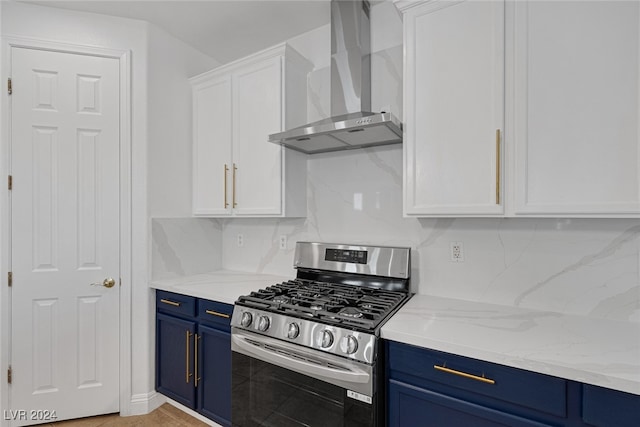 kitchen with blue cabinets, stainless steel gas range oven, wall chimney range hood, and white cabinets