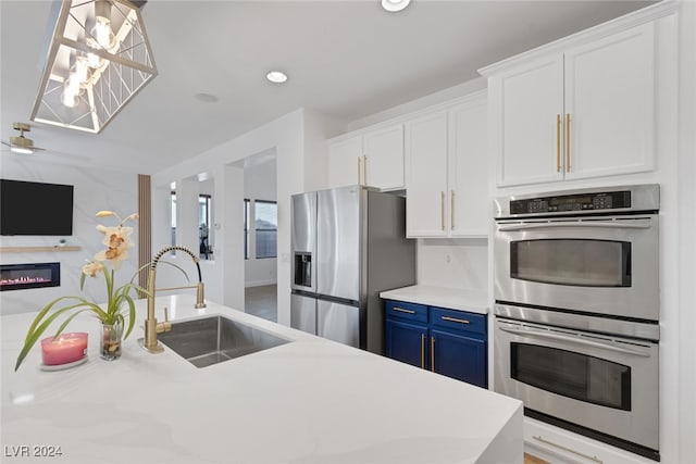 kitchen featuring blue cabinetry, white cabinets, appliances with stainless steel finishes, and sink