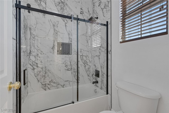 bathroom featuring bath / shower combo with glass door and toilet