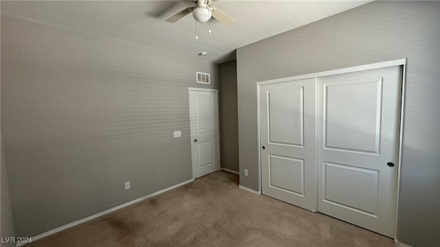 unfurnished bedroom featuring ceiling fan, a closet, and light carpet