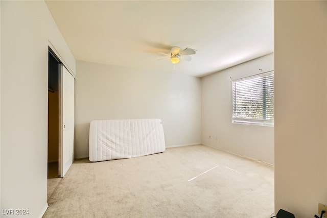 unfurnished bedroom featuring a closet, light carpet, and ceiling fan