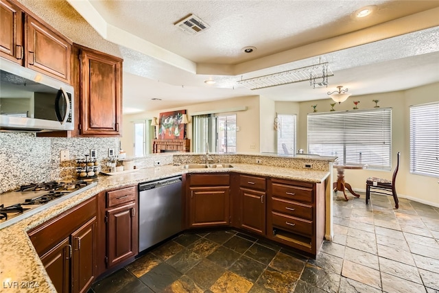 kitchen with stainless steel appliances, kitchen peninsula, decorative backsplash, and a wealth of natural light