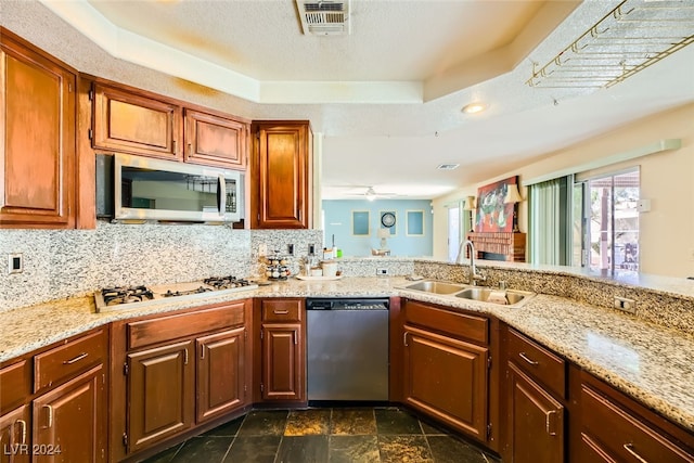 kitchen with ceiling fan, a raised ceiling, sink, a textured ceiling, and stainless steel appliances