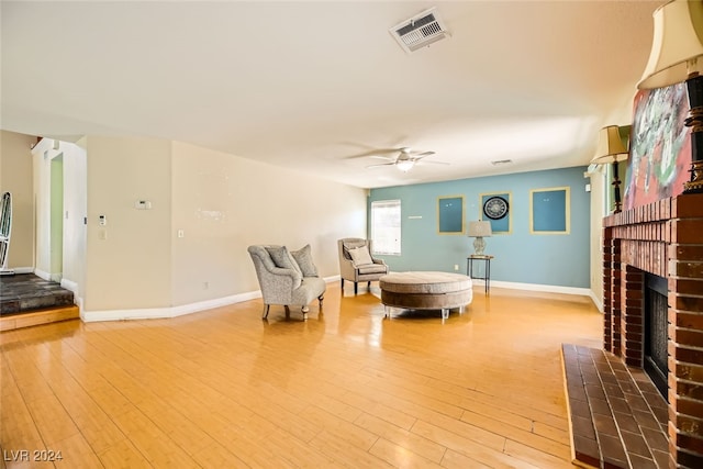 living room with ceiling fan, light wood-type flooring, and a fireplace