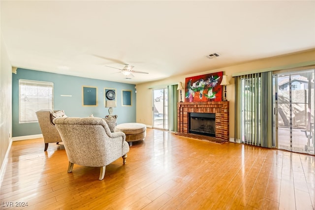 living room featuring a brick fireplace, a wealth of natural light, and light hardwood / wood-style flooring