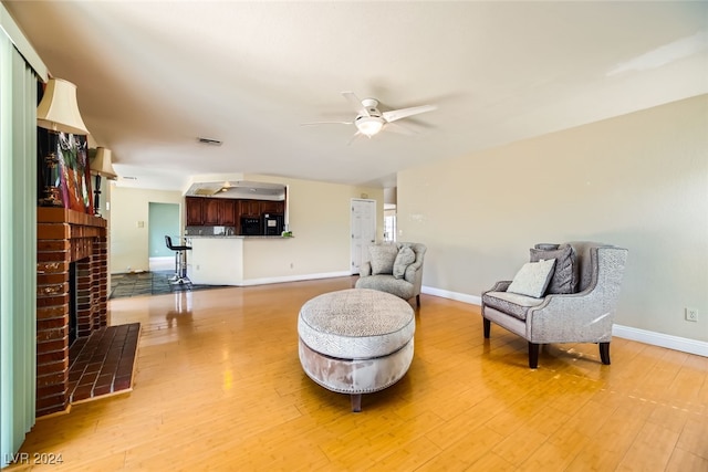 sitting room with a fireplace, ceiling fan, and hardwood / wood-style floors