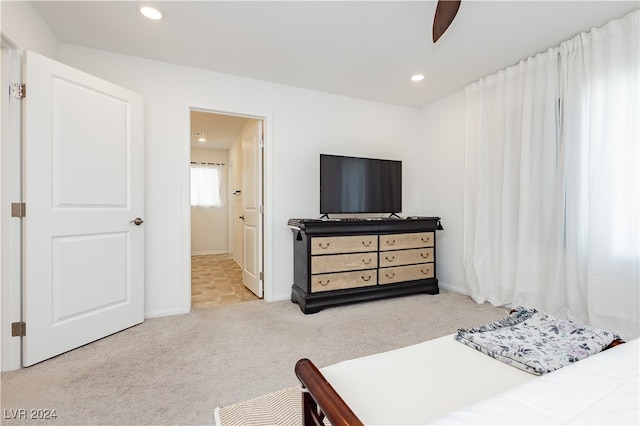 bedroom with ceiling fan, light colored carpet, and ensuite bathroom