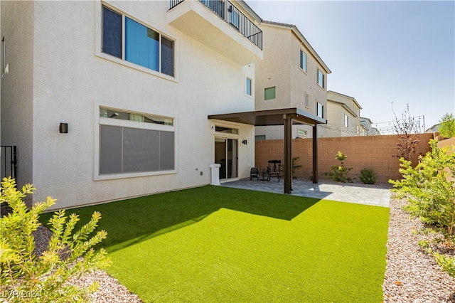 back of house featuring a balcony, a lawn, and a patio