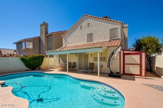 rear view of house featuring a fenced in pool and a patio