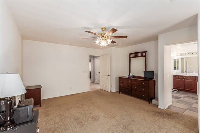 bedroom featuring light carpet, ceiling fan, and ensuite bath