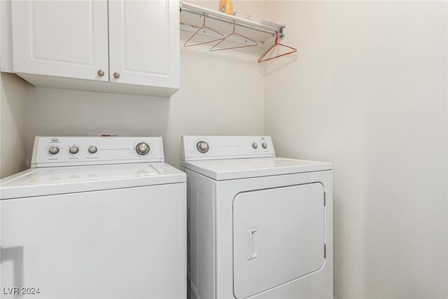 clothes washing area with cabinets and washer and clothes dryer