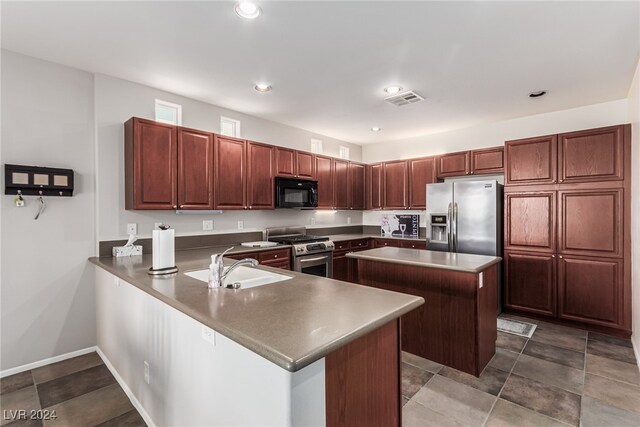 kitchen featuring kitchen peninsula, a breakfast bar area, stainless steel appliances, a center island, and sink