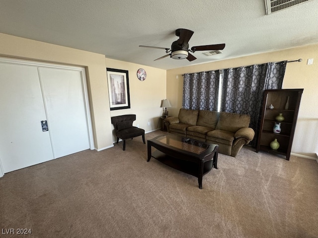 living room featuring ceiling fan, light colored carpet, and a textured ceiling