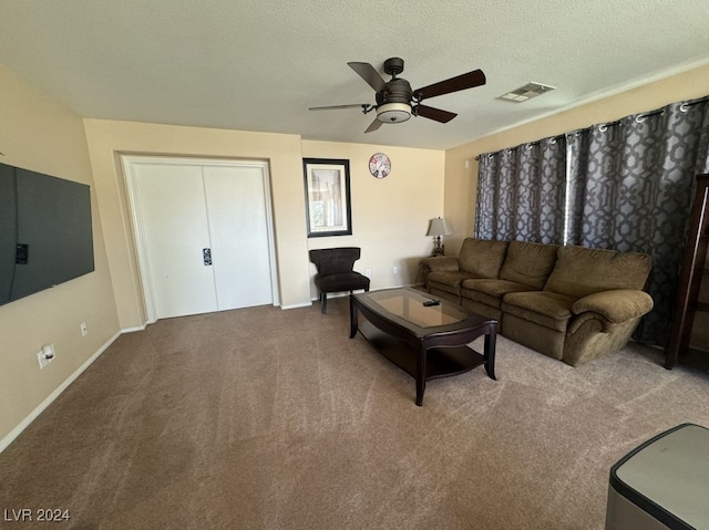 living room with a textured ceiling, carpet flooring, and ceiling fan