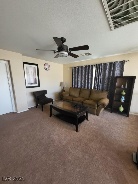 living room with ceiling fan, a textured ceiling, and carpet