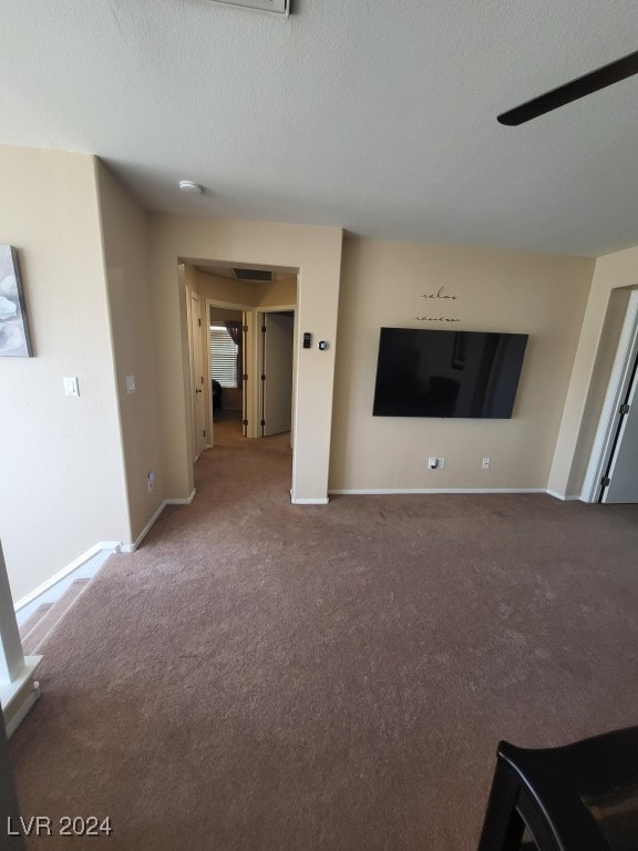 unfurnished living room with a textured ceiling, carpet floors, and ceiling fan