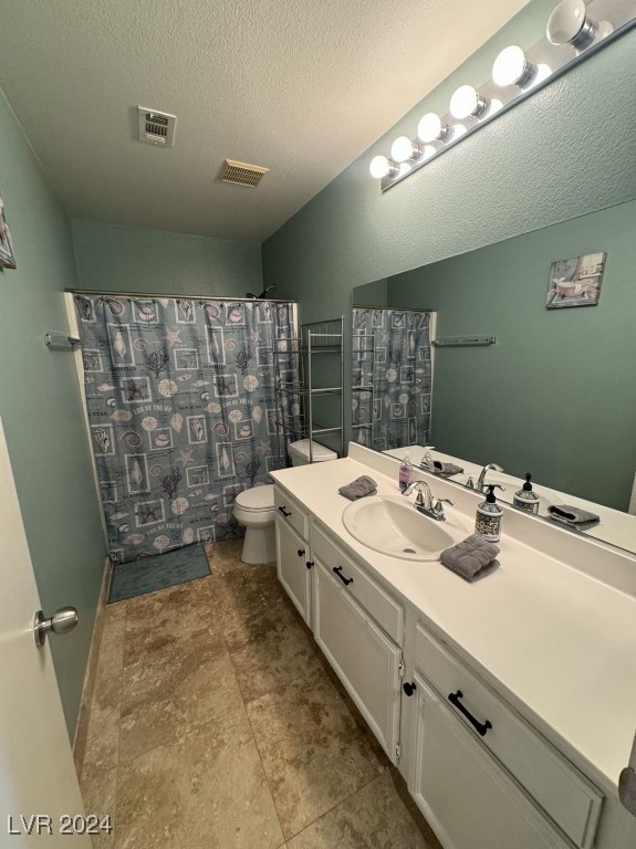 bathroom featuring a shower with shower curtain, a textured ceiling, vanity, and toilet