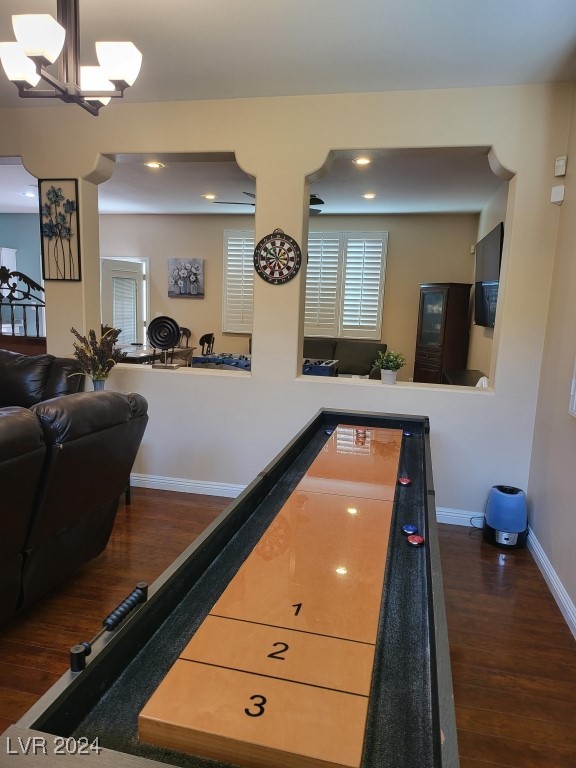 recreation room with a notable chandelier and dark wood-type flooring