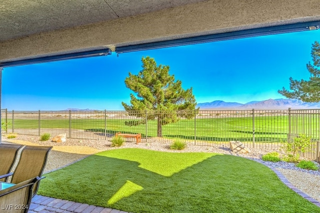 view of yard featuring a fenced backyard, a mountain view, and a rural view