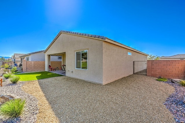 rear view of property with a patio, fence, and stucco siding