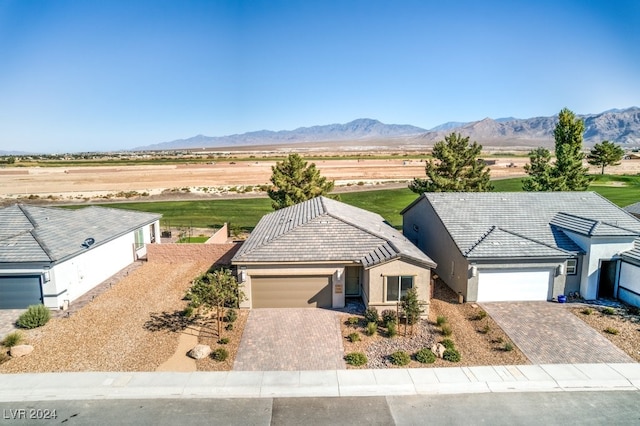 view of front of property with decorative driveway, a mountain view, and an attached garage