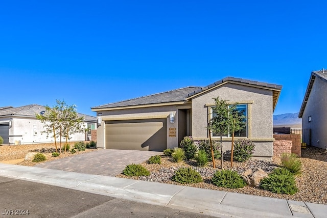 view of front of property featuring decorative driveway, an attached garage, and stucco siding