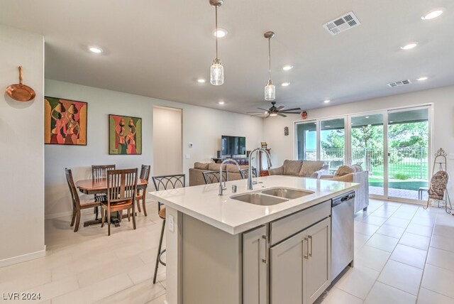 kitchen featuring ceiling fan, an island with sink, hanging light fixtures, sink, and dishwasher