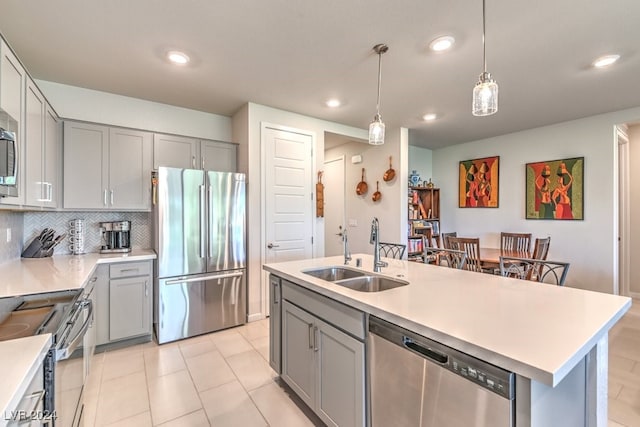 kitchen with an island with sink, appliances with stainless steel finishes, light countertops, and a sink