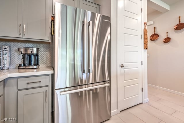 kitchen with baseboards, light countertops, backsplash, gray cabinets, and freestanding refrigerator