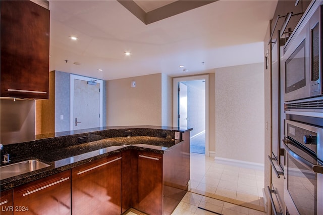 kitchen featuring appliances with stainless steel finishes, dark stone counters, light tile patterned flooring, and sink