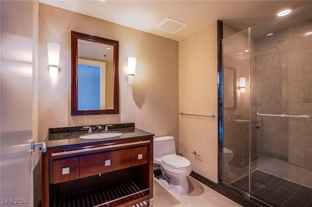 bathroom featuring tile patterned flooring, vanity, toilet, and a shower with door