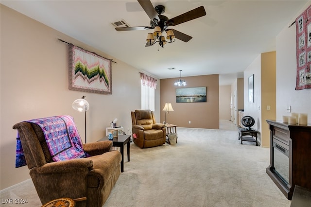 living area featuring ceiling fan with notable chandelier and light colored carpet