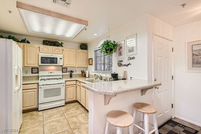 kitchen featuring light tile patterned flooring, kitchen peninsula, a kitchen breakfast bar, white appliances, and light brown cabinets