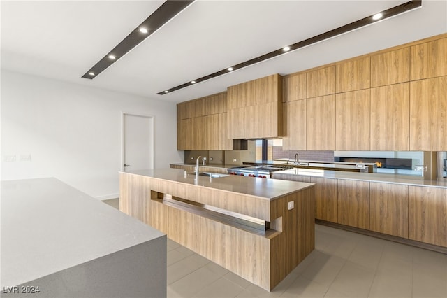 kitchen with a spacious island, backsplash, sink, and stainless steel stove