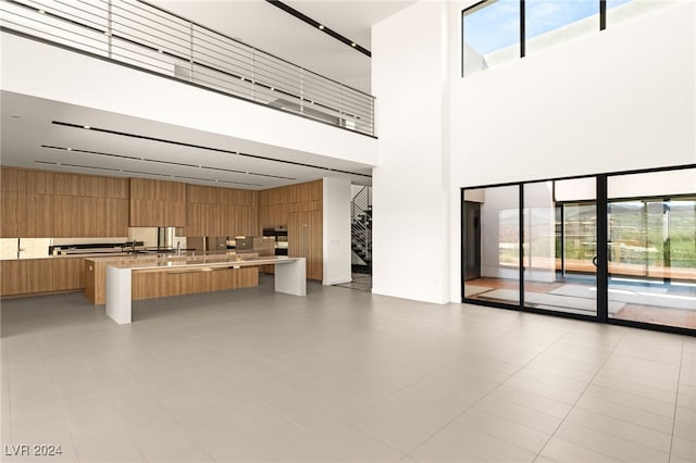 interior space with light tile patterned floors, a high ceiling, kitchen peninsula, and a kitchen breakfast bar