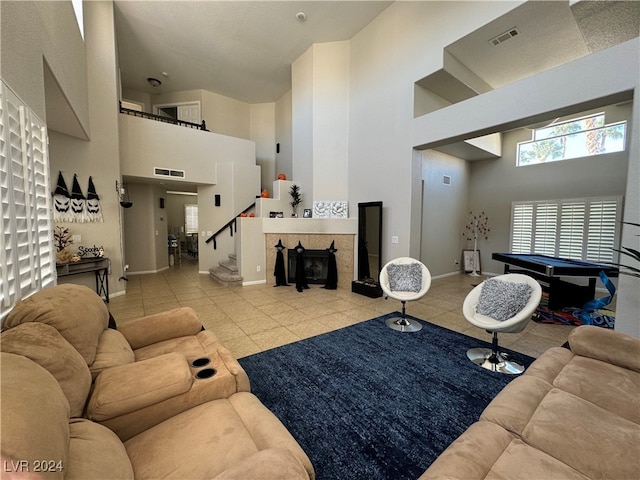 tiled living room featuring a tiled fireplace, a high ceiling, and pool table